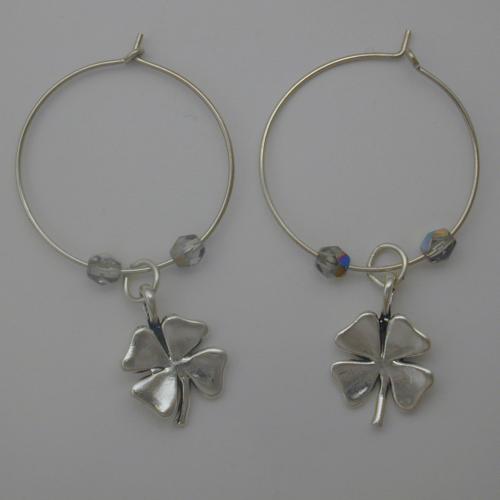Sterling silver hoop with a sterling silver four leaf clover flanked by two clear Czech glass beads.