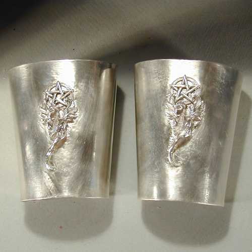 These impressive arm guards are made from solid sterling silver.  They are 4 inches high and cover all but an inch gap along the inside of the wrist.  These have a dragon and pentagram design on them, but other designs can be used, or they can be made plain.