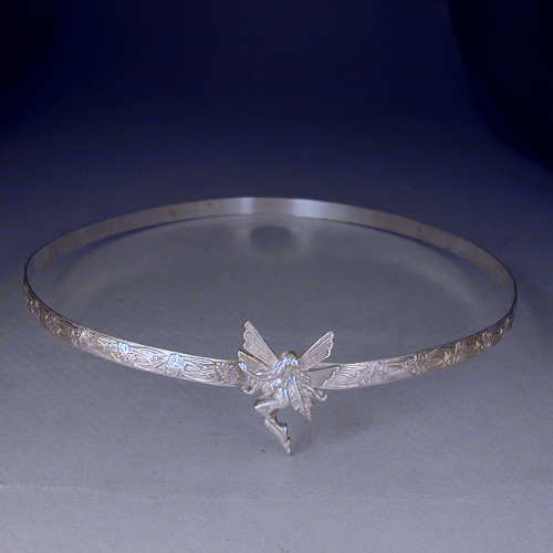 A fairy is set on this 1/3 inch sterling silver floral patterned band.