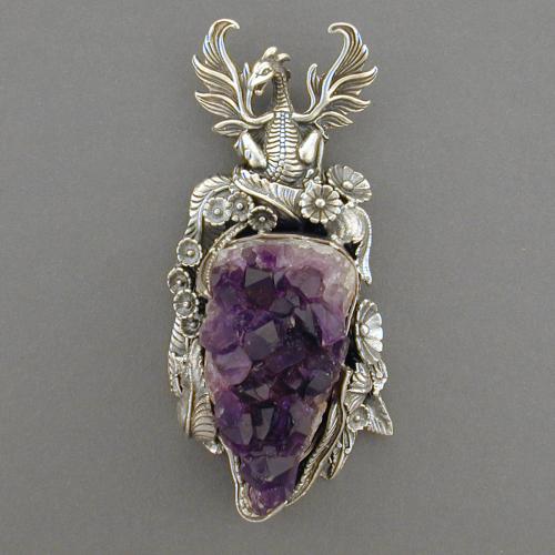 This amethyst cluster is topped by a lovely dragon. Around this crystal cave are leaves and flowers. Drink in the naturally dark purple color of this stone and let it intoxicate you.