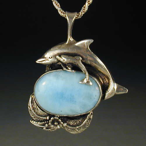 These frolicking dolphins dance over sunlit waves of Larimar set in sterling silver.