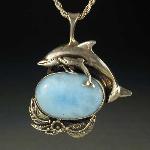 These frolicking dolphins dance over sunlit waves of Larimar set in sterling silver.